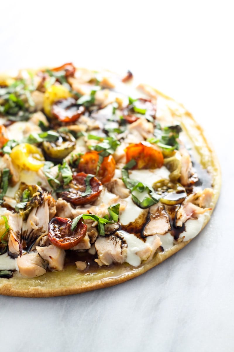 Pizza topped with chicken, roasted tomatoes, mozzarella, fresh basil and balsamic vinegar.