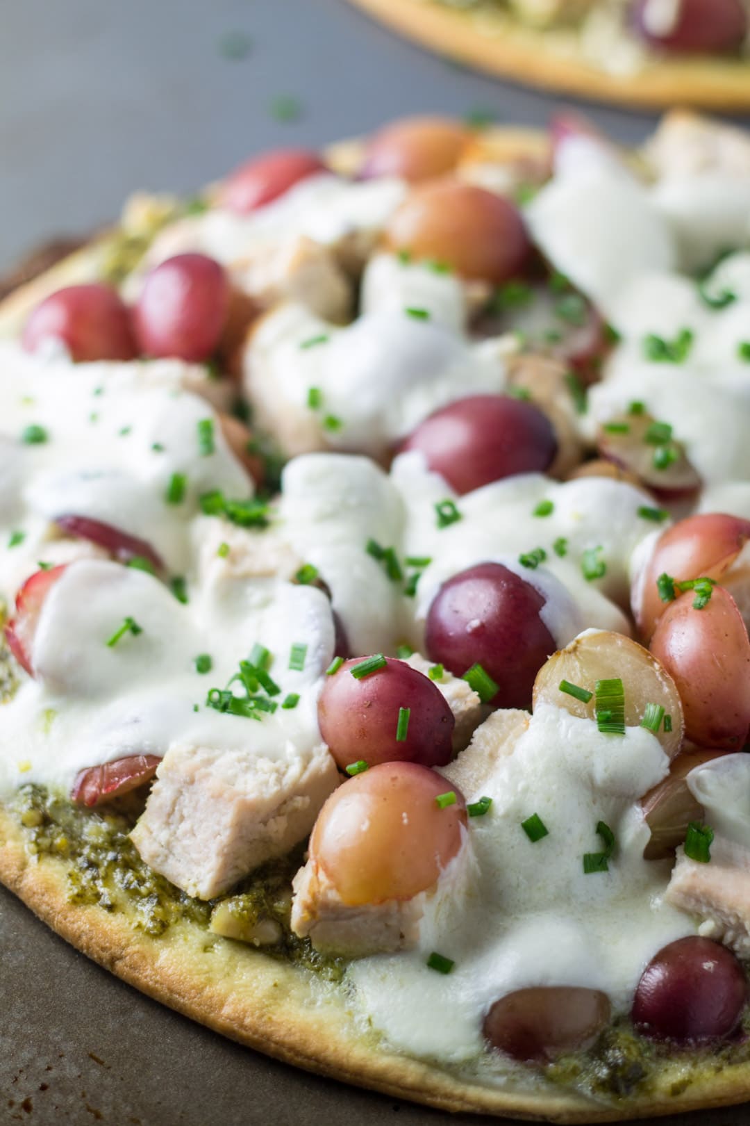 Low FODMAP pizza made with pesto, chicken, red grapes, and mozzarella