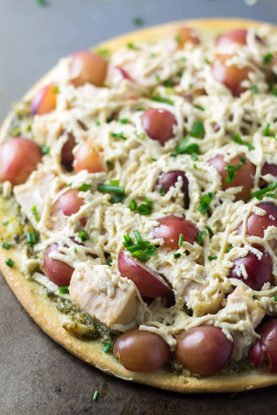 A pizza made with grapes, chicken, pesto, and dairy-free mozzarella-style cheese.