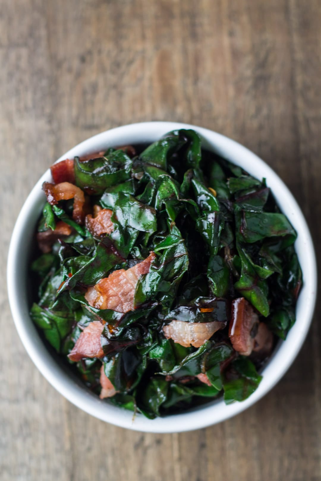 Looking down at a small bowl filled with sauteed Swiss chard with bacon