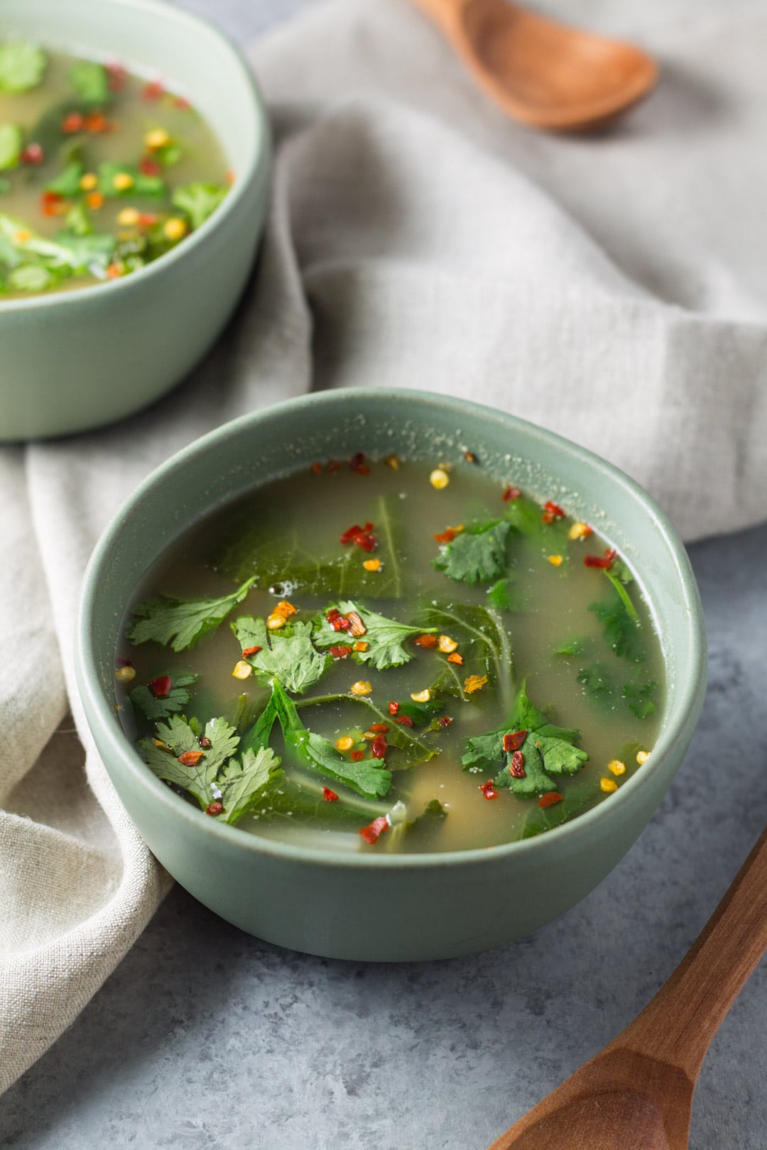 Two bowls of tom yum soup with wooden spoons