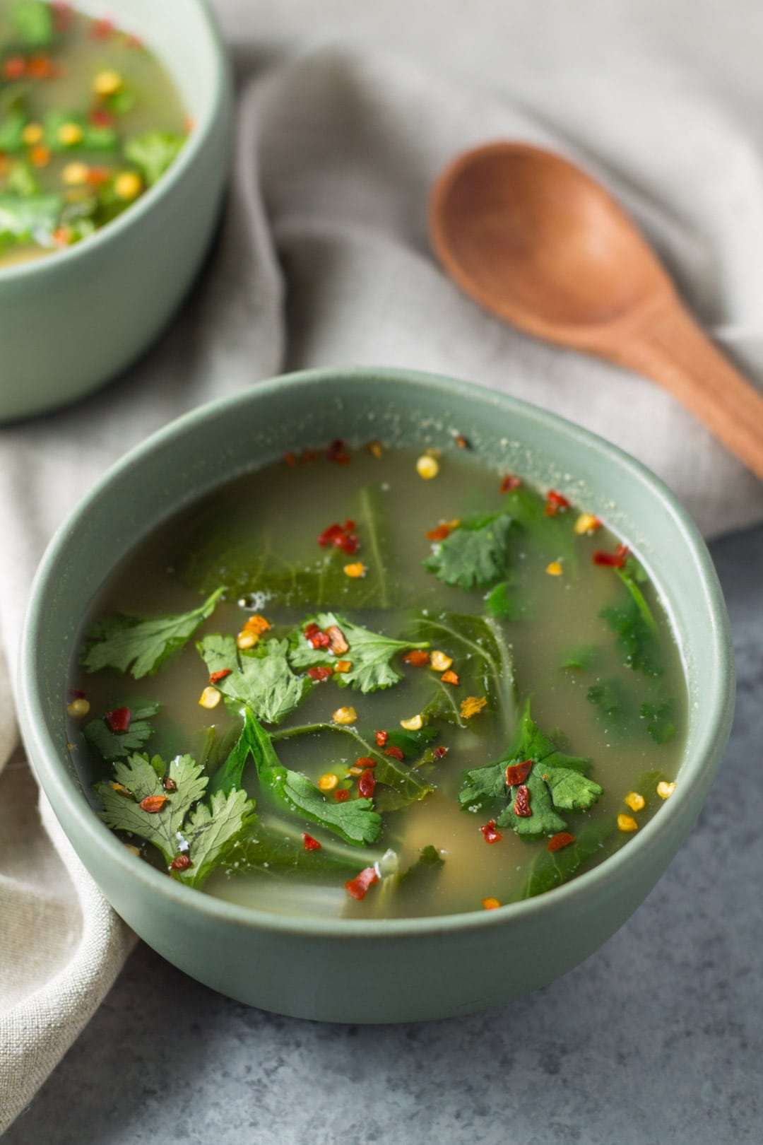 Bowls of Tom Yum soup with a wooden spoon