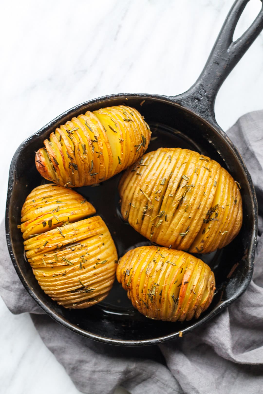 Skillet filled with low FODMAP Hasselback Potatoes with Rosemary