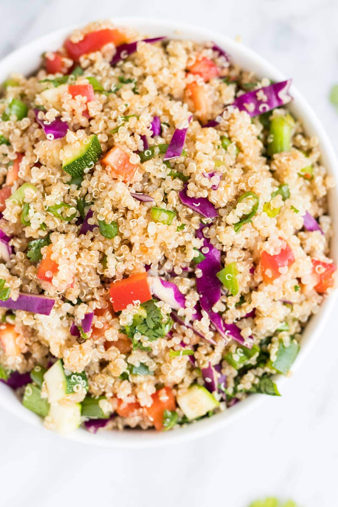 Overhead close up shot of a white bowl filled with Low FODMAP Rainbow Quinoa Salad