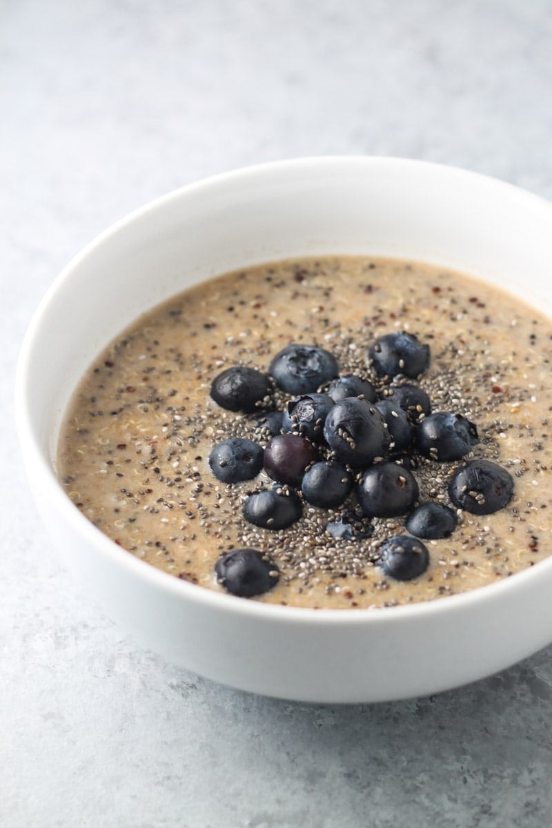 A bowl of low FODMAP breakfast quinoa topped with fresh blueberries and chia seeds. 