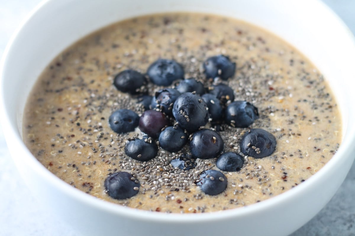 A bowl of cooked quinoa mixed with low FODMAP milk and topped with blueberries. 