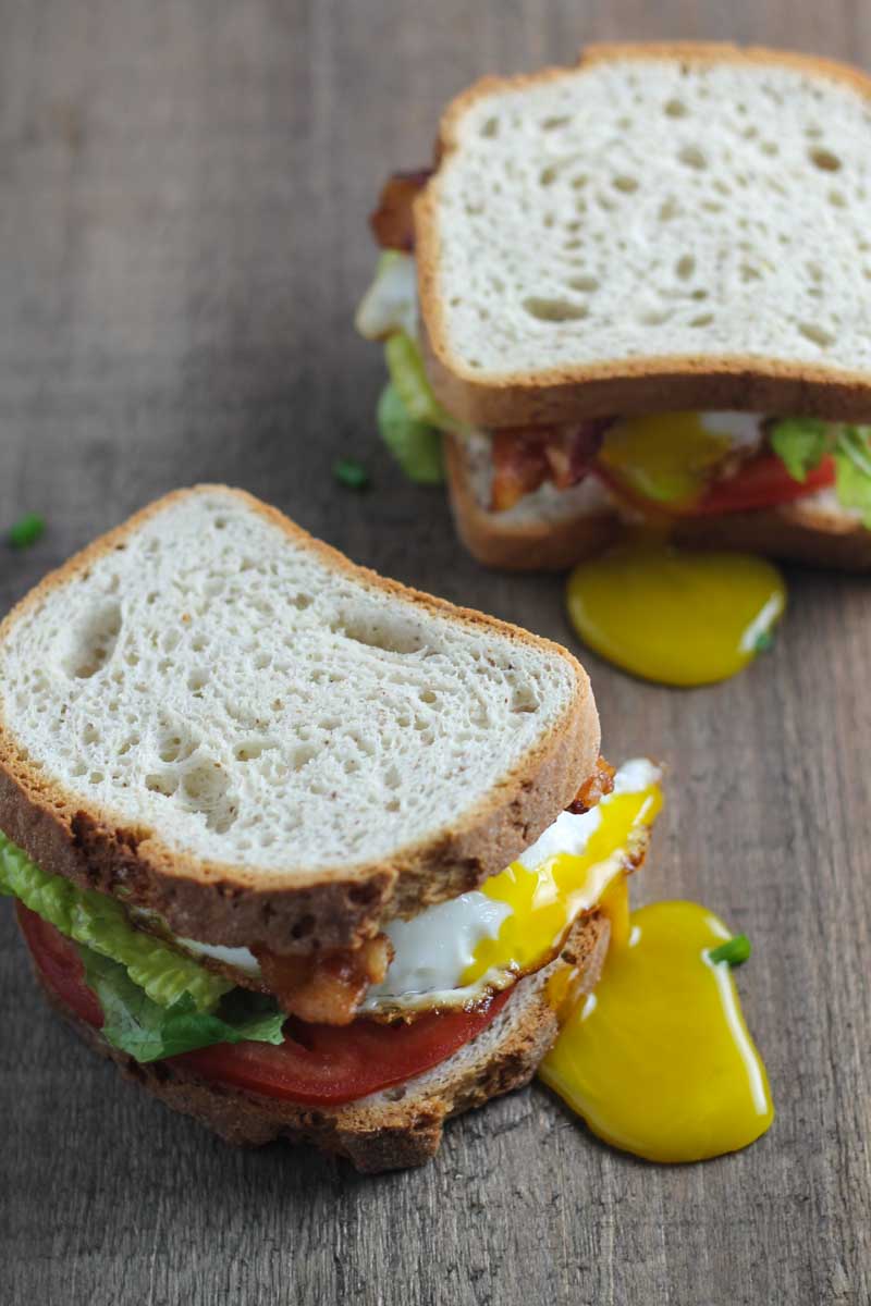 Two low FODMAP BLT sandwiches made with a drippy fried egg. 