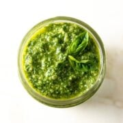 Low FODMAP pesto in a small mason jar topped with fresh basil leaves