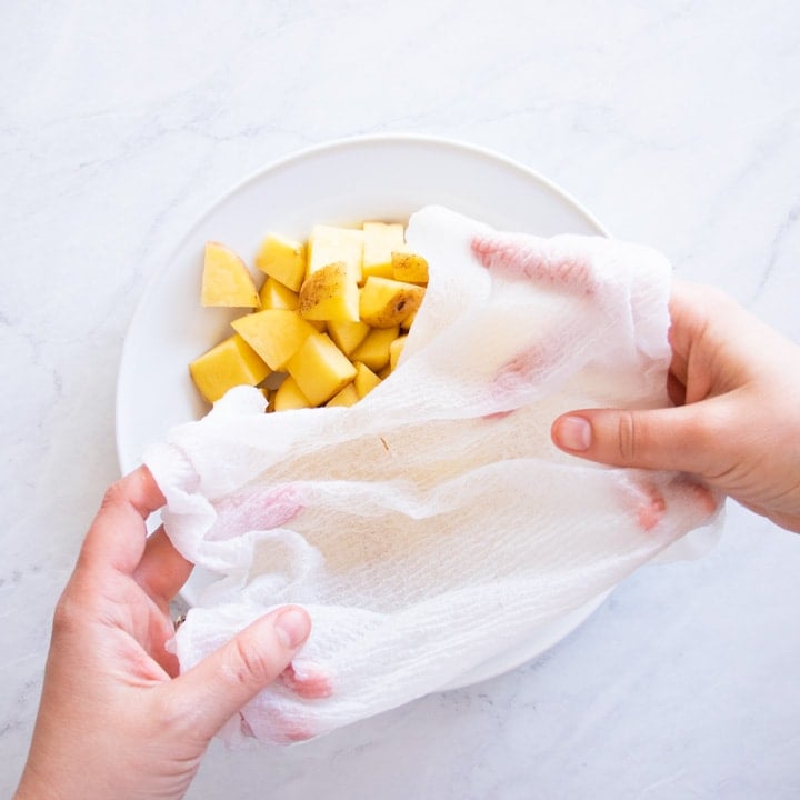 Covering a plate of diced potatoes with a damp paper towel.