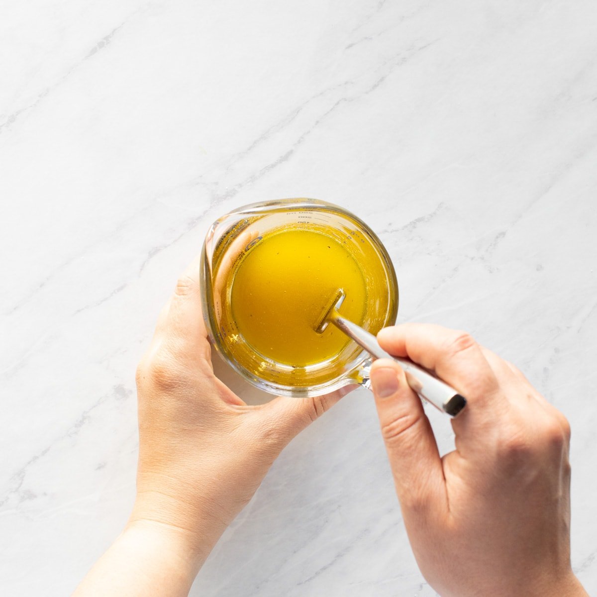 Whisking together a simple lemon vinaigrette in a small glass measuring cup