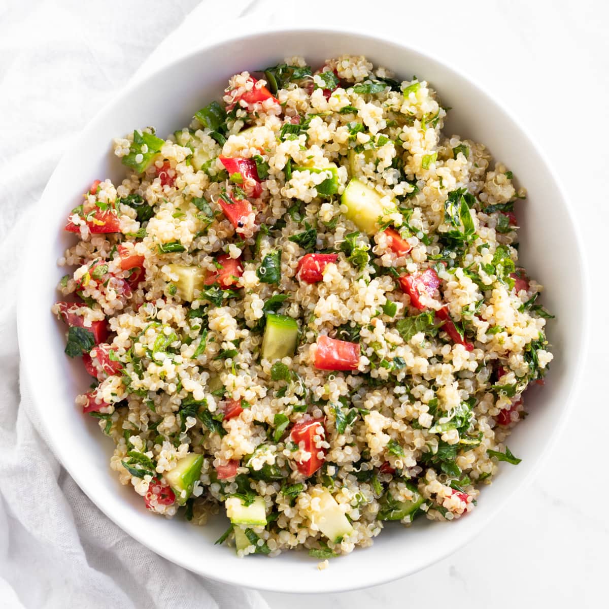 A shallow white bowl filled with quinoa tabbouleh