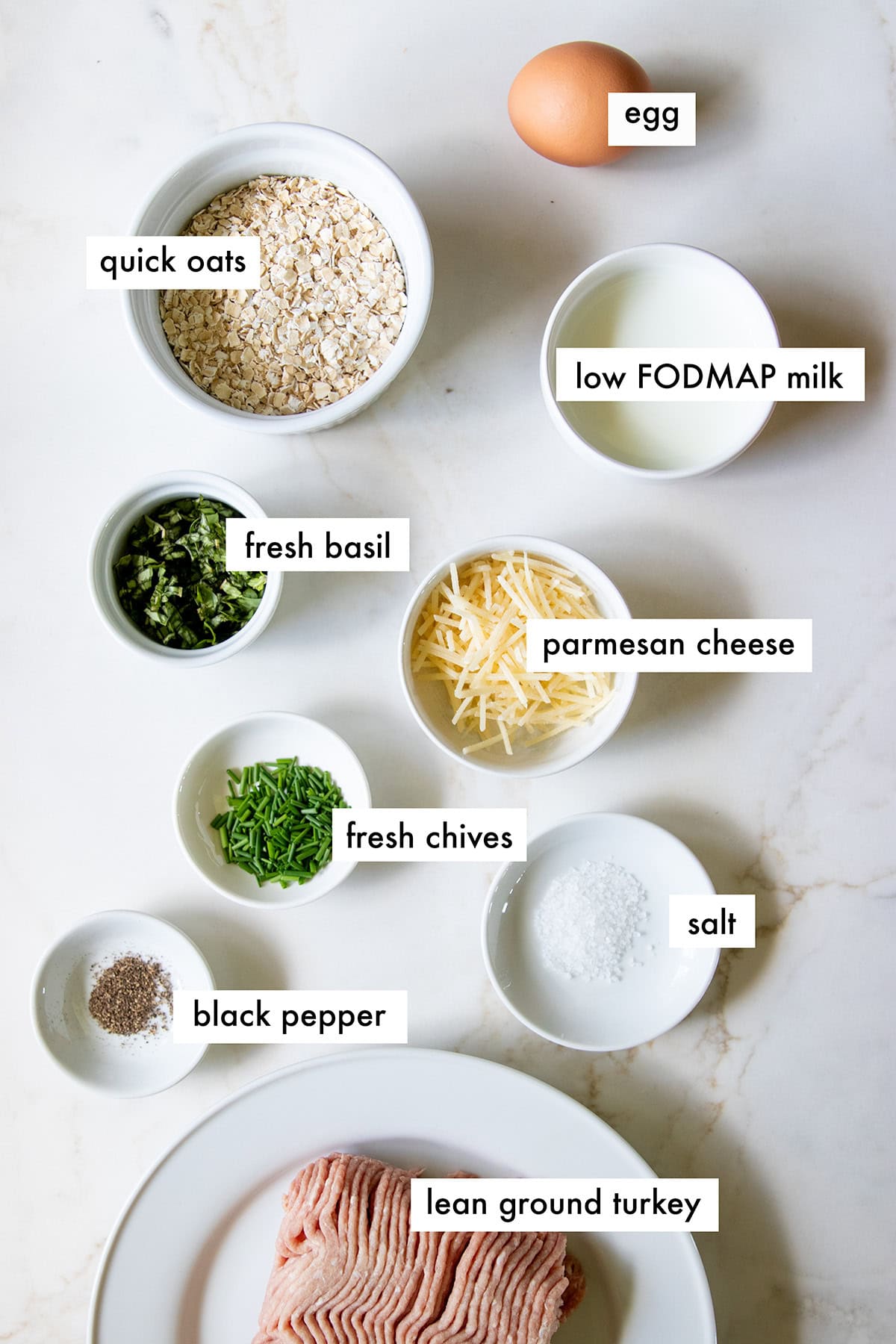 Ingredients needed for low FODMAP pesto turkey meatballs are prepared and measured out into individual dishes ready for baking.
