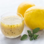 Side shot of a cup filled with low FODMAP lemon vinaigrette and a lemon