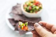 Close up shot of blue corn chip filled with low FODMAP salsa
