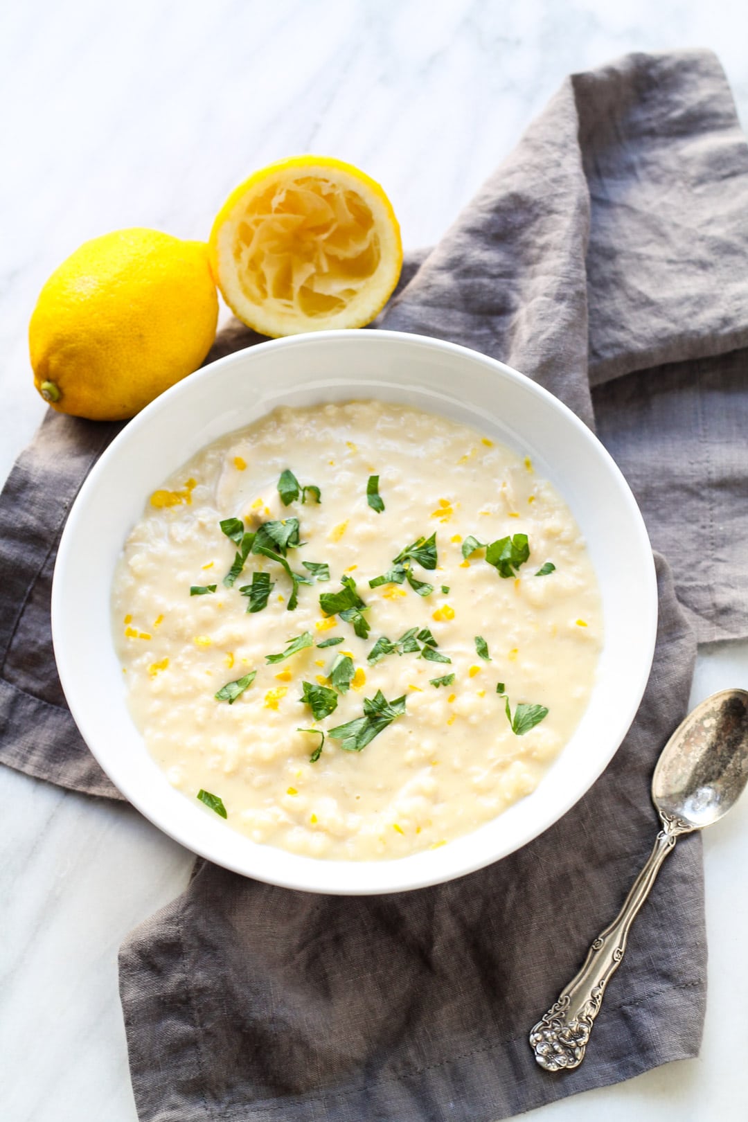 Looking down at a shallow bowl filled with a lemon-flavored soup made with rice and chicken.