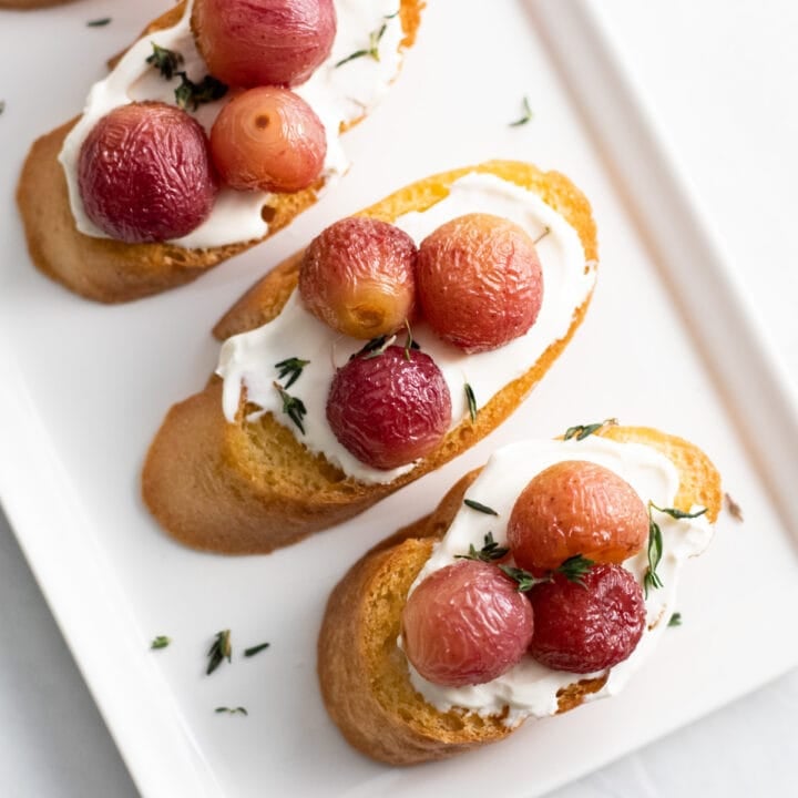 toasted baguette slices topped with lactose-free cream cheese, roasted grapes and fresh thyme leaves