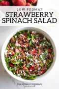 A bowl of spinach salad topped with strawberries, pecans and feta cheese. A black text overlay reads "Low FODMAP Strawberry Spinach Salad."