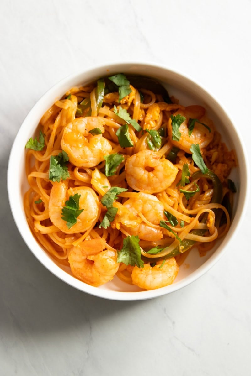 A bowl of Low FODMAP Shrimp Pad Thai sits on a white countertop.