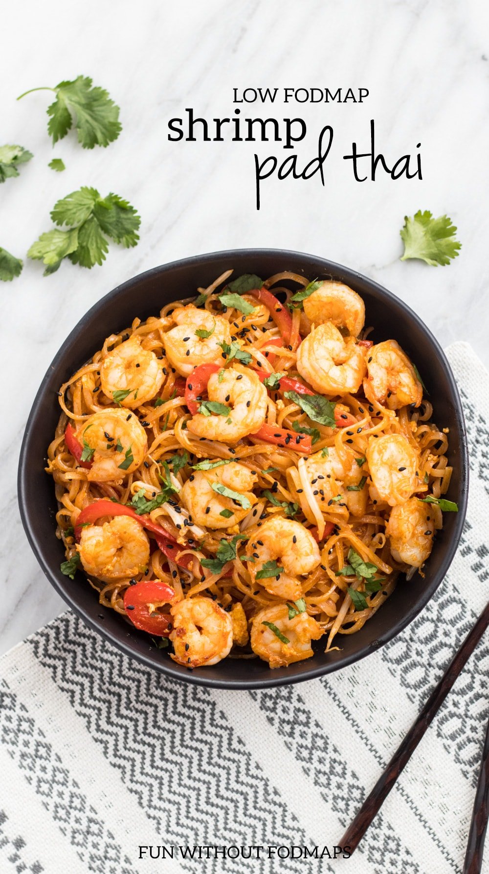 Low FODMAP shrimp pad thai in a black bowl on a white marble background. Black text reads "low FODMAP shrimp pad thai" in the upper right corner.