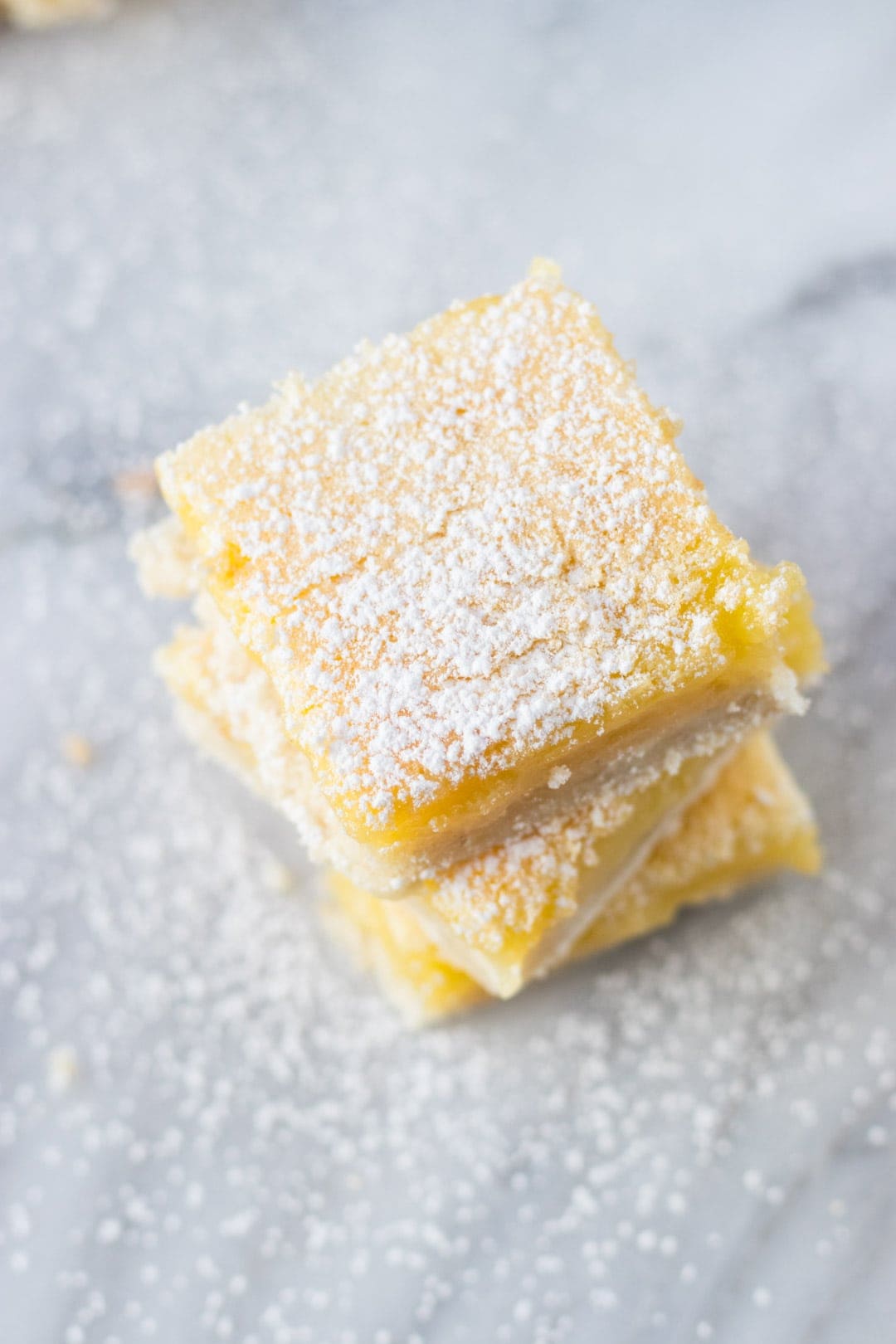 Stack of low FODMAP lemon bars dusted with powdered sugar.