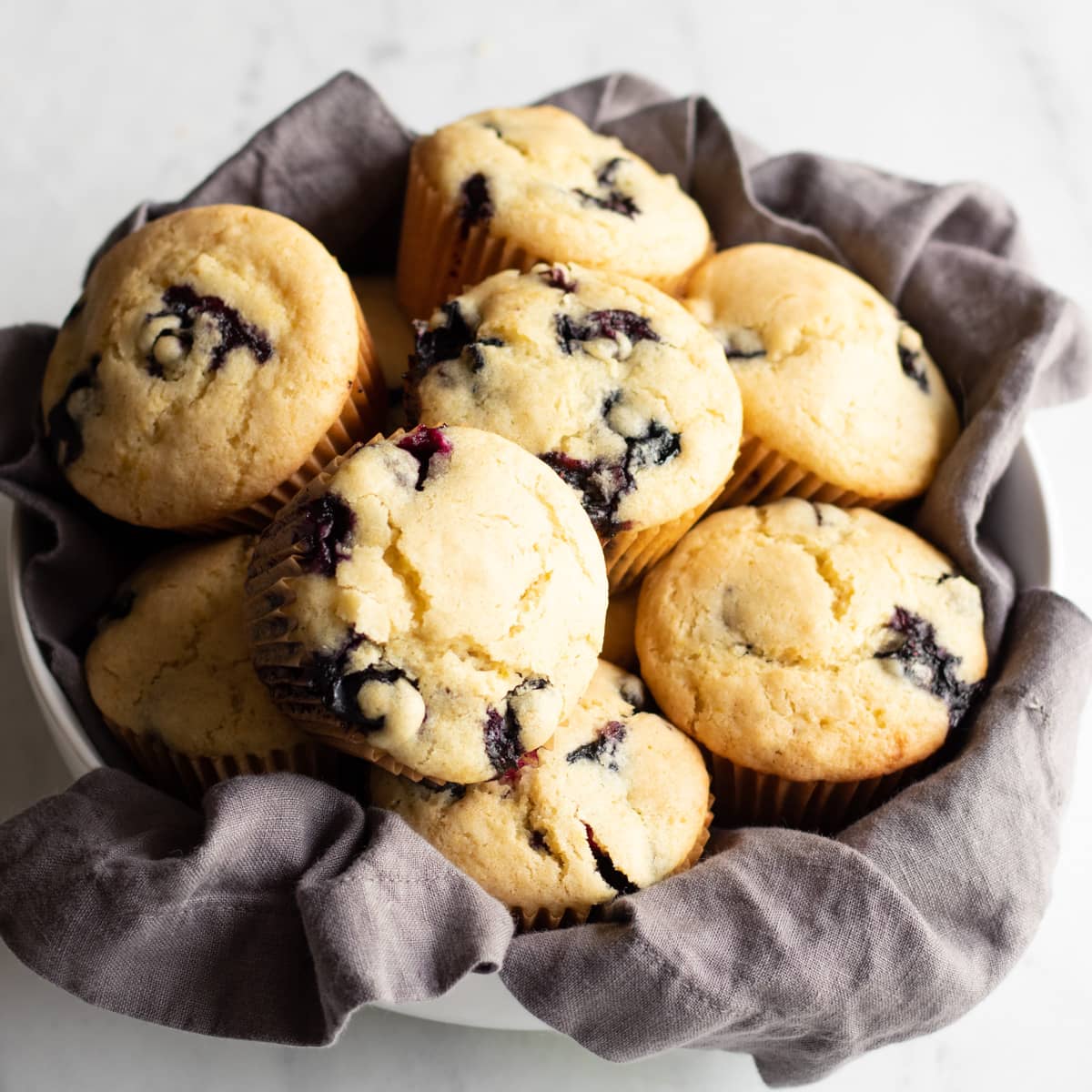 gluten-free blueberry muffins in a bowl lined with a cloth napkin