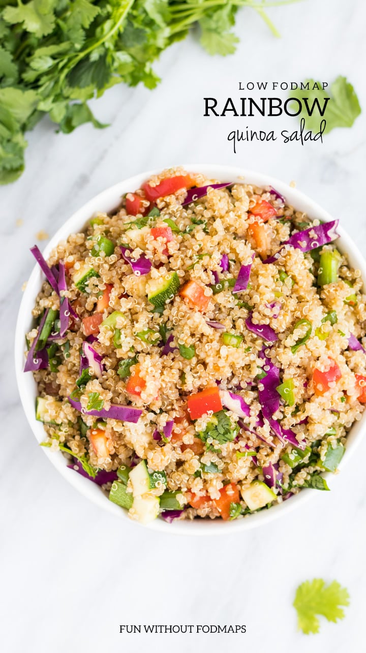 A large white bowl filled with low FODMAP rainbow quinoa salad. It is sitting on a white marble slap and has dark gray text overlayed in the upper right. The text reads Low FODMAP Rainbow Quinoa Salad. There is also text centered at the bottom that says FUN WITHOUT FODMAPS.