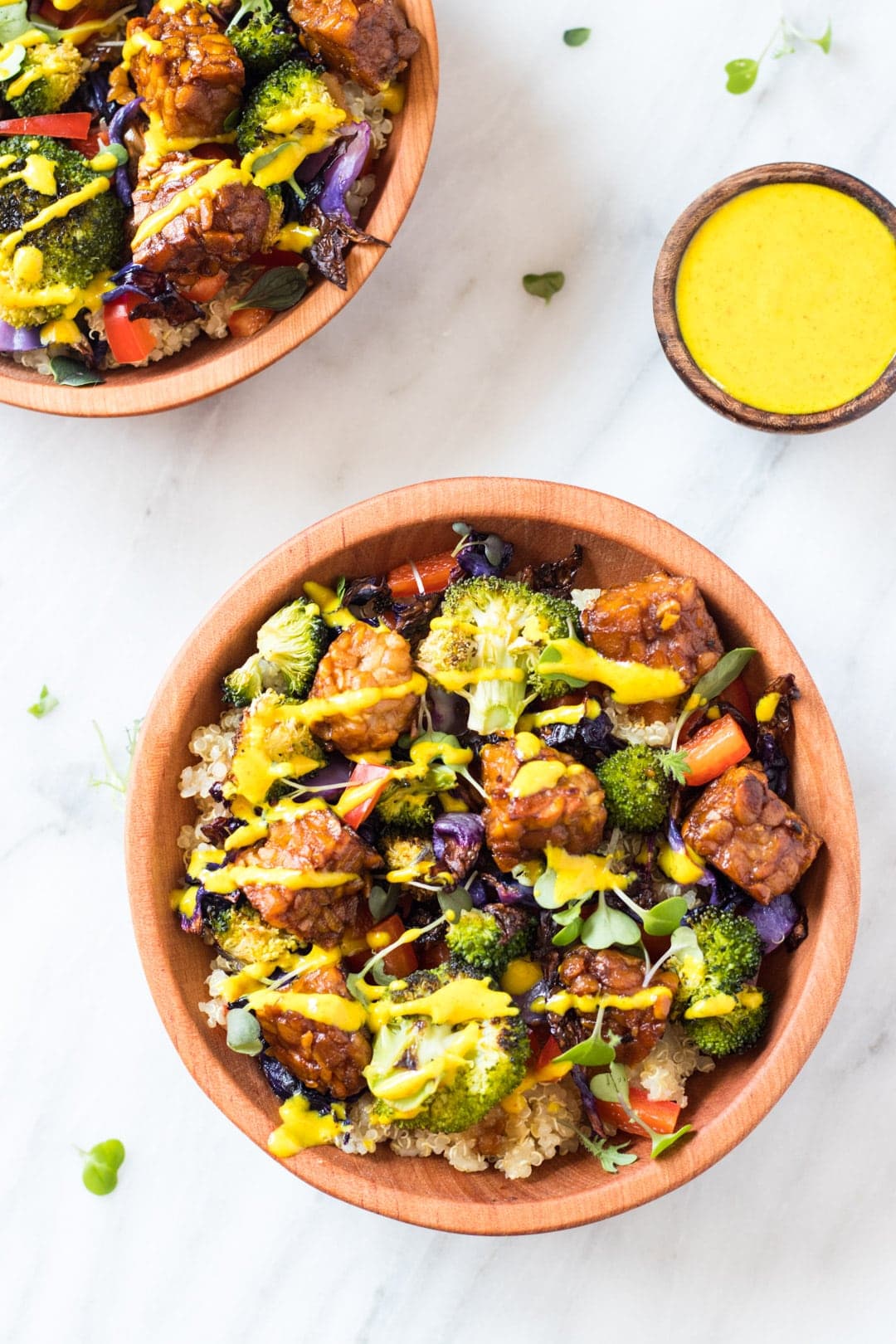 Two low FODMAP rainbow bliss bowls topped with a drizzle of turmeric-tahini dressing