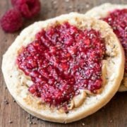 A toasted brown rice English muffin topped with peanut butter and raspberry chia jam.