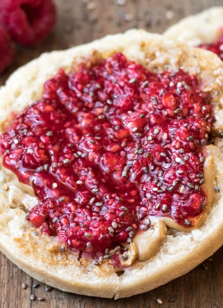 A toasted brown rice English muffin topped with peanut butter and raspberry chia jam.