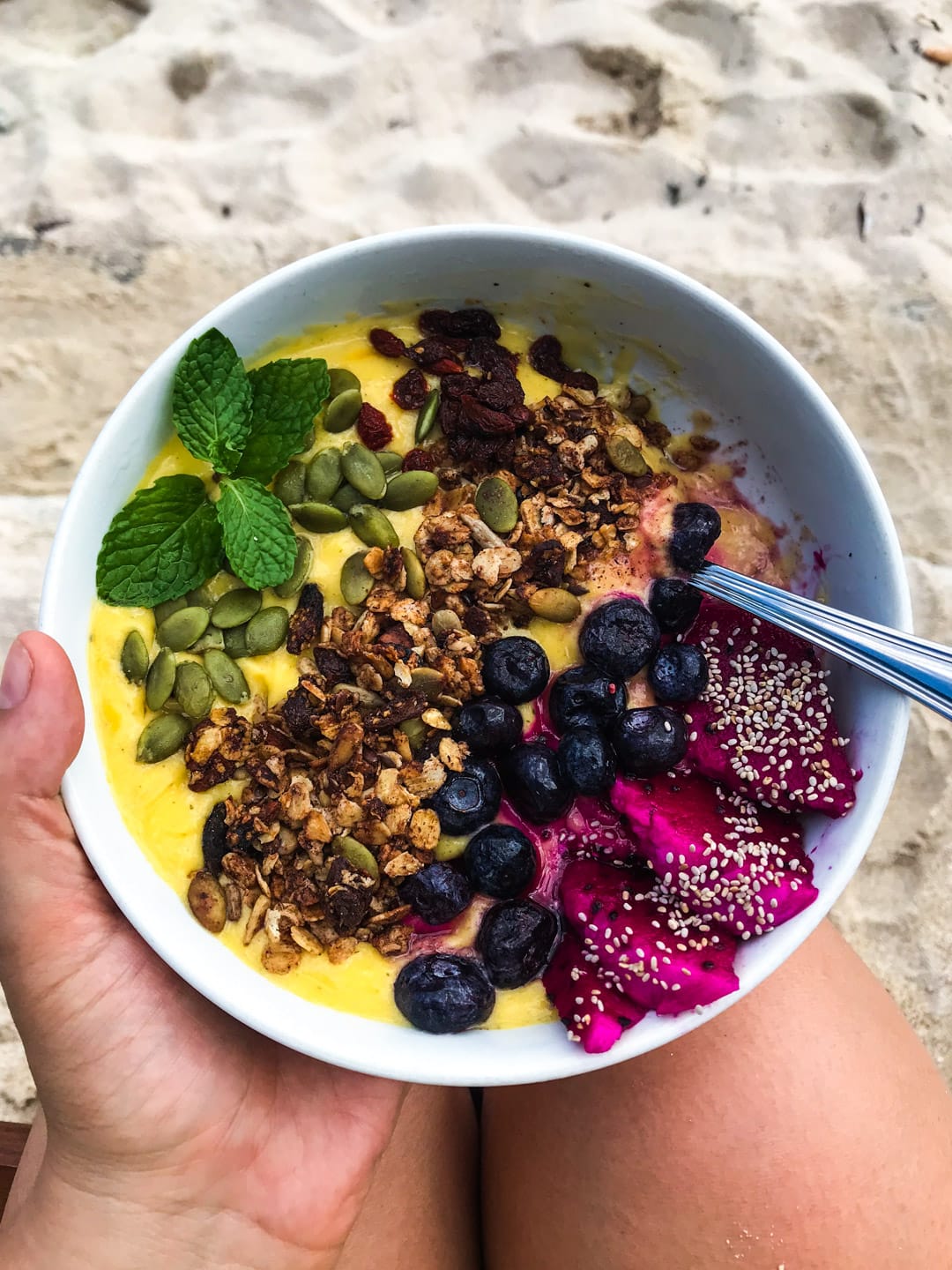 A yellow mango smoothie bowl topped with colorful tropical fruit from Ginger and Jamu cafe in Lembongan, Bali
