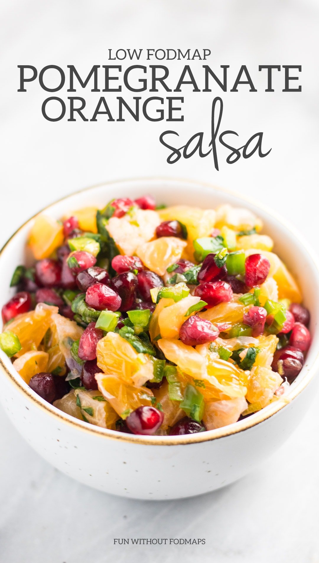 Low FODMAP Pomegranate Orange Salsa in a white bowl on a white marble background with a gray text overlay of the recipe's name. 