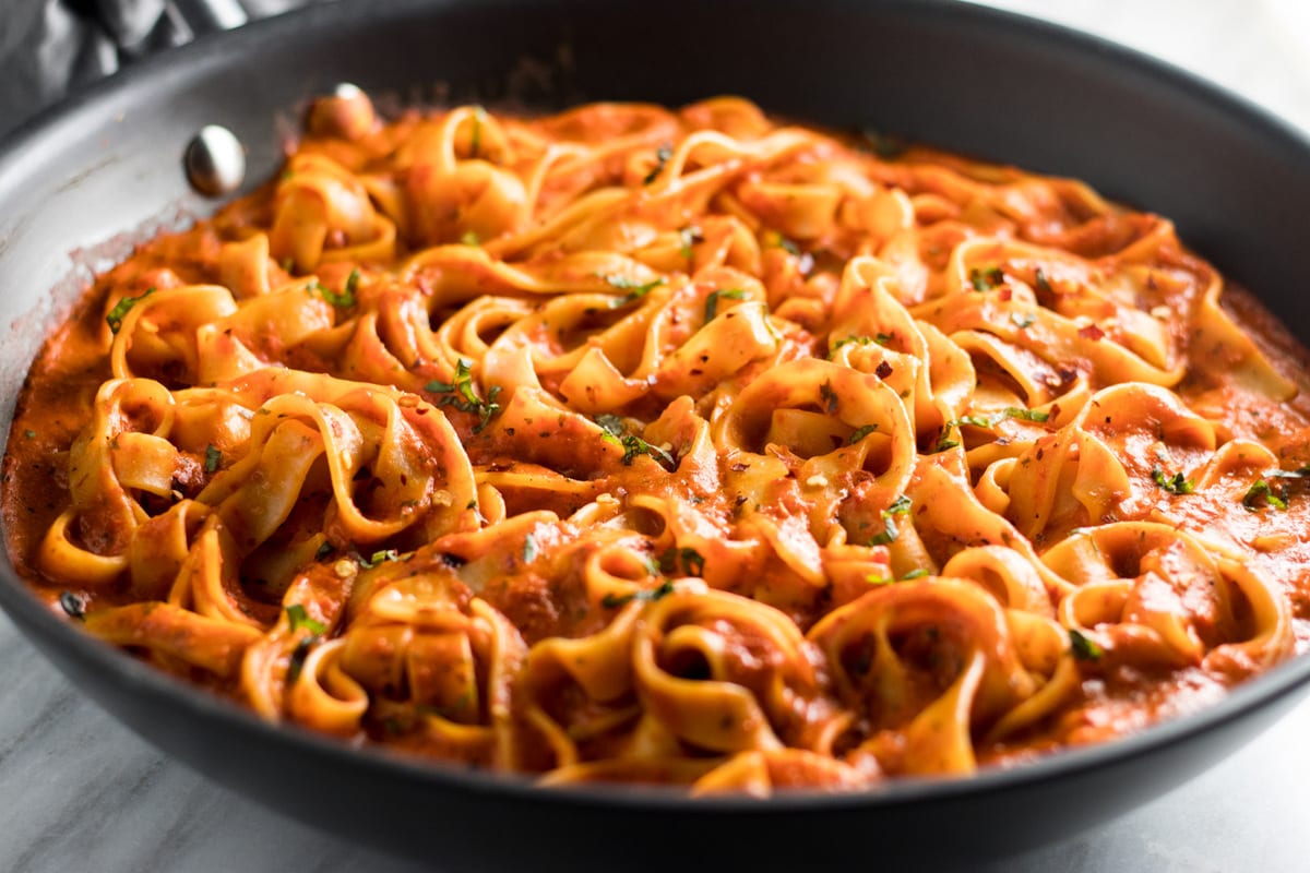 Horizontal close-up of Low FODMAP Roasted Red Pepper Pasta in a black skillet.