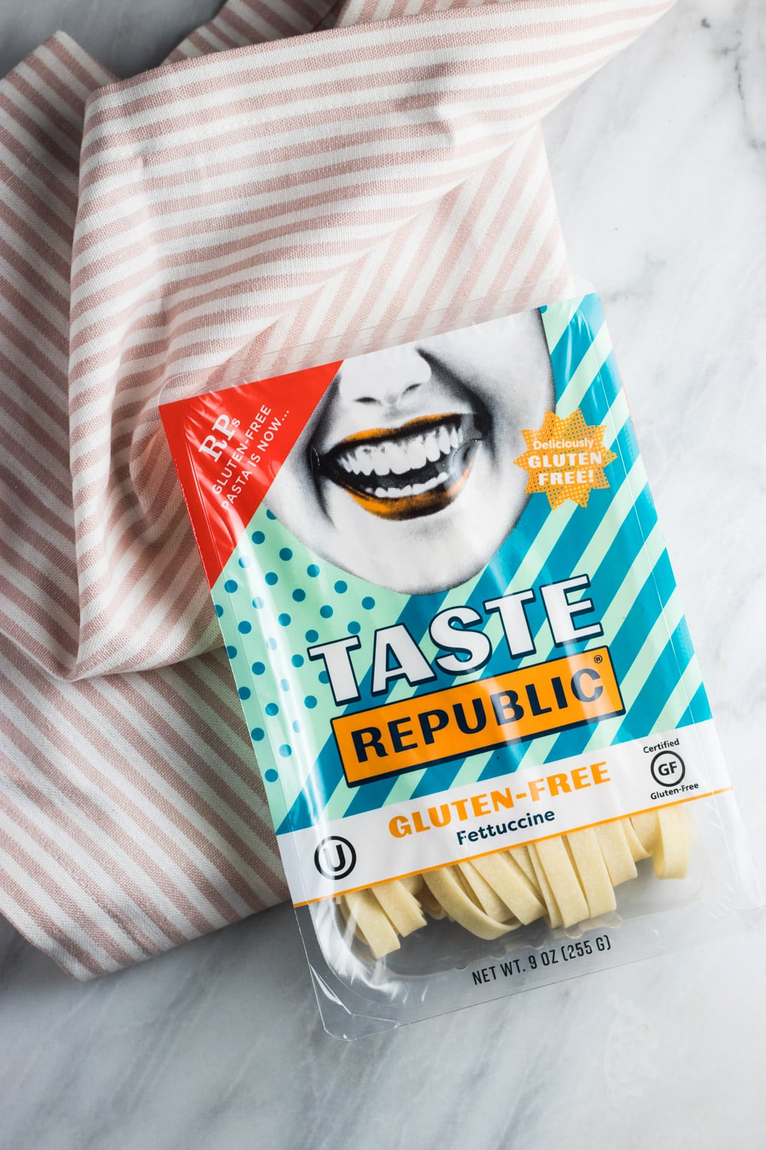 A package of Taste Republic Gluten Free Pasta on a light pink and white striped cloth napkin