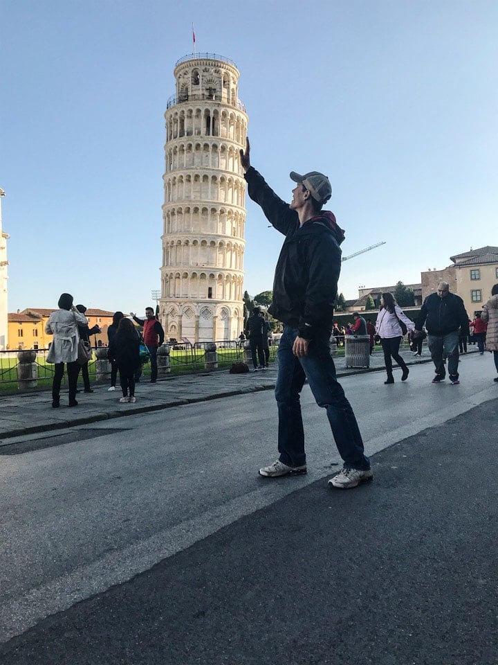Man pretending to hold up the leaning tower of Pisa because when in Italy