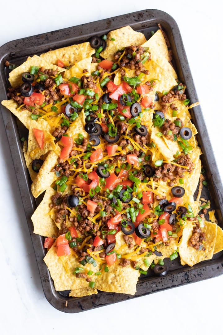 An overhead shot of a jelly roll pan filled with loaded low FODMPA lentil nachos.