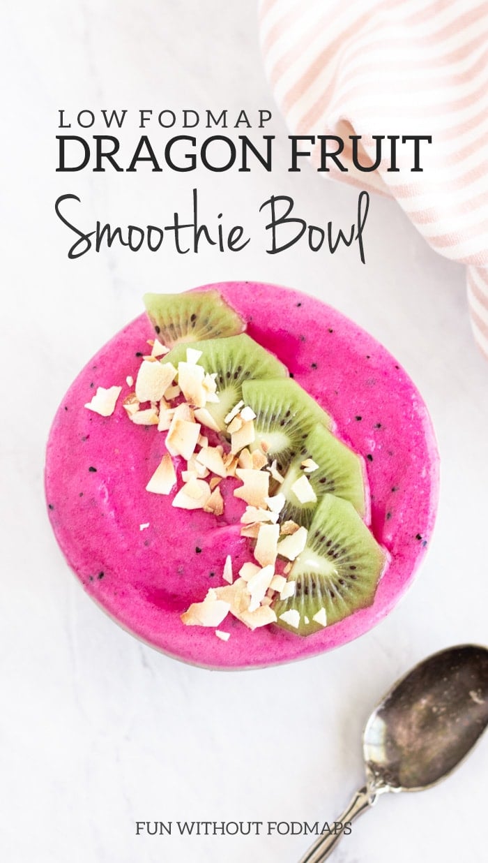 Overhead shot of a hot pink low FODMAP dragon fruit smoothie bowl topped with kiwi slices and coconut flakes. The bowl is sitting on a white marble slab and is framed by a white and light pink striped napkin and an antique spoon. Dark gray text reads Low FODMAP Dragon Fruit Smoothie Bowl and FUN WITHOUT FODMAPS.