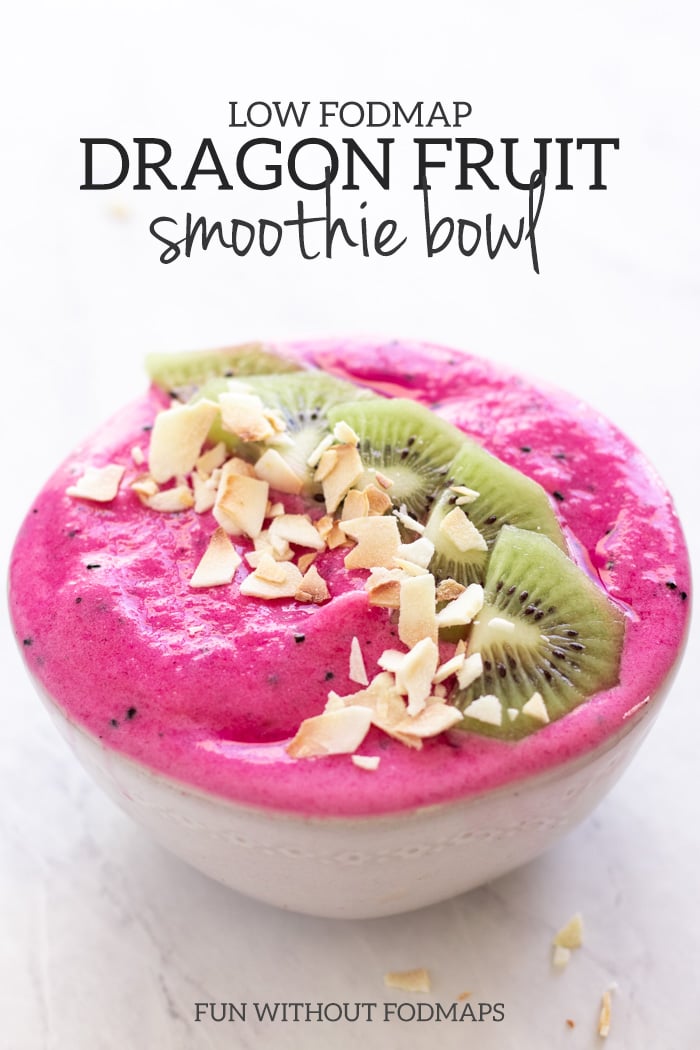 A hot pink low FODMAP dragon fruit smoothie bowl is topped with kiwi slices and coconut flakes in a white bowl on a white marble slab. Dark gray text reads Low FODMAP Dragon Fruit Smoothie Bowl and Fun Without FODMAPs.