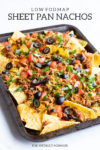 A close up of low FODMAP sheet pan nachos or corn chips topped with sliced black olives, diced fresh tomatoes, cilantro, ground turkey, green onion tops, and melty cheddar. Dark gray text at the top of the image reads Low FODMAP Sheet Pan Nachos. At the bottom it also says FUN WITHOUT FODMAPS.