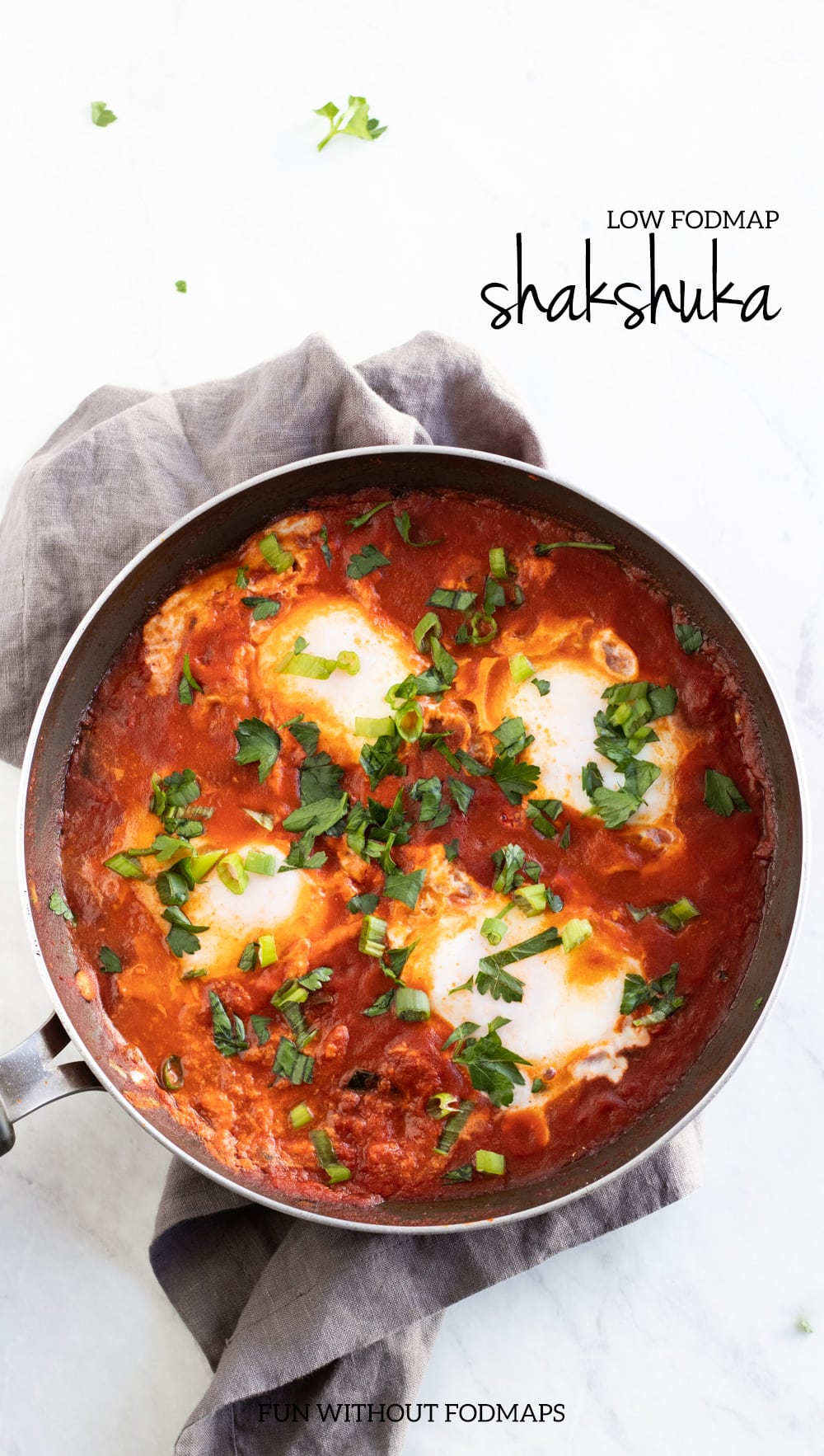 An overhead shot of low FODMAP shakshuka on a white marble slab. A dark gray text overlay reads "low FODMAP shakshuka" in the upper right corner