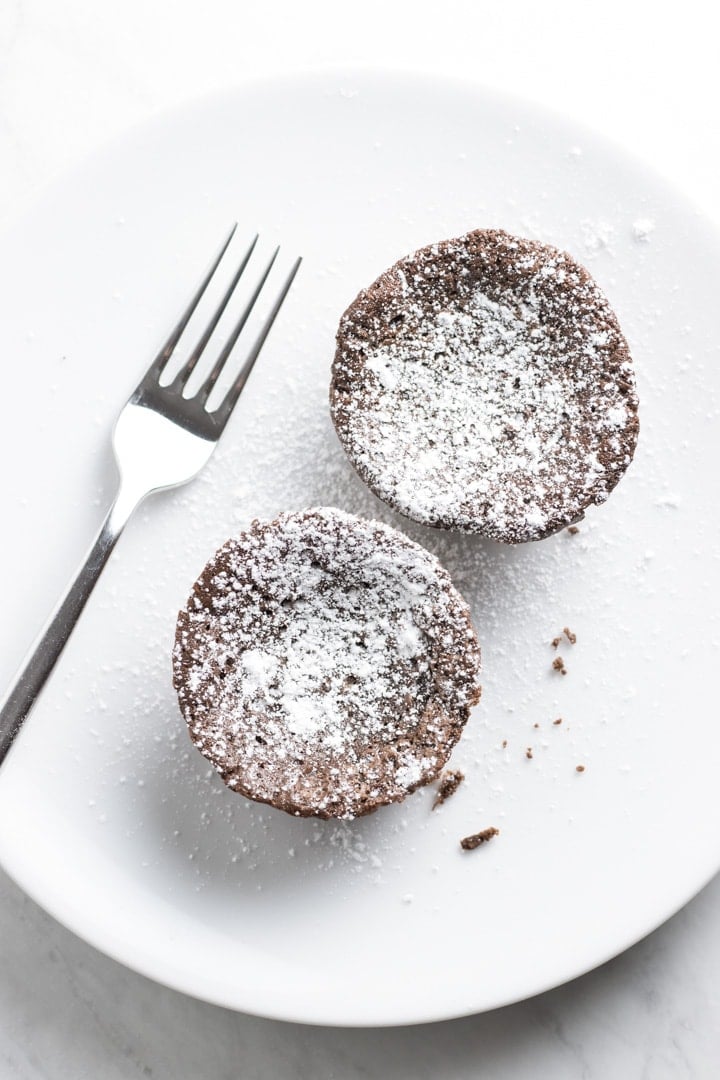 Two mini low FODMAP chocolate tortes on a white plate with a fork.