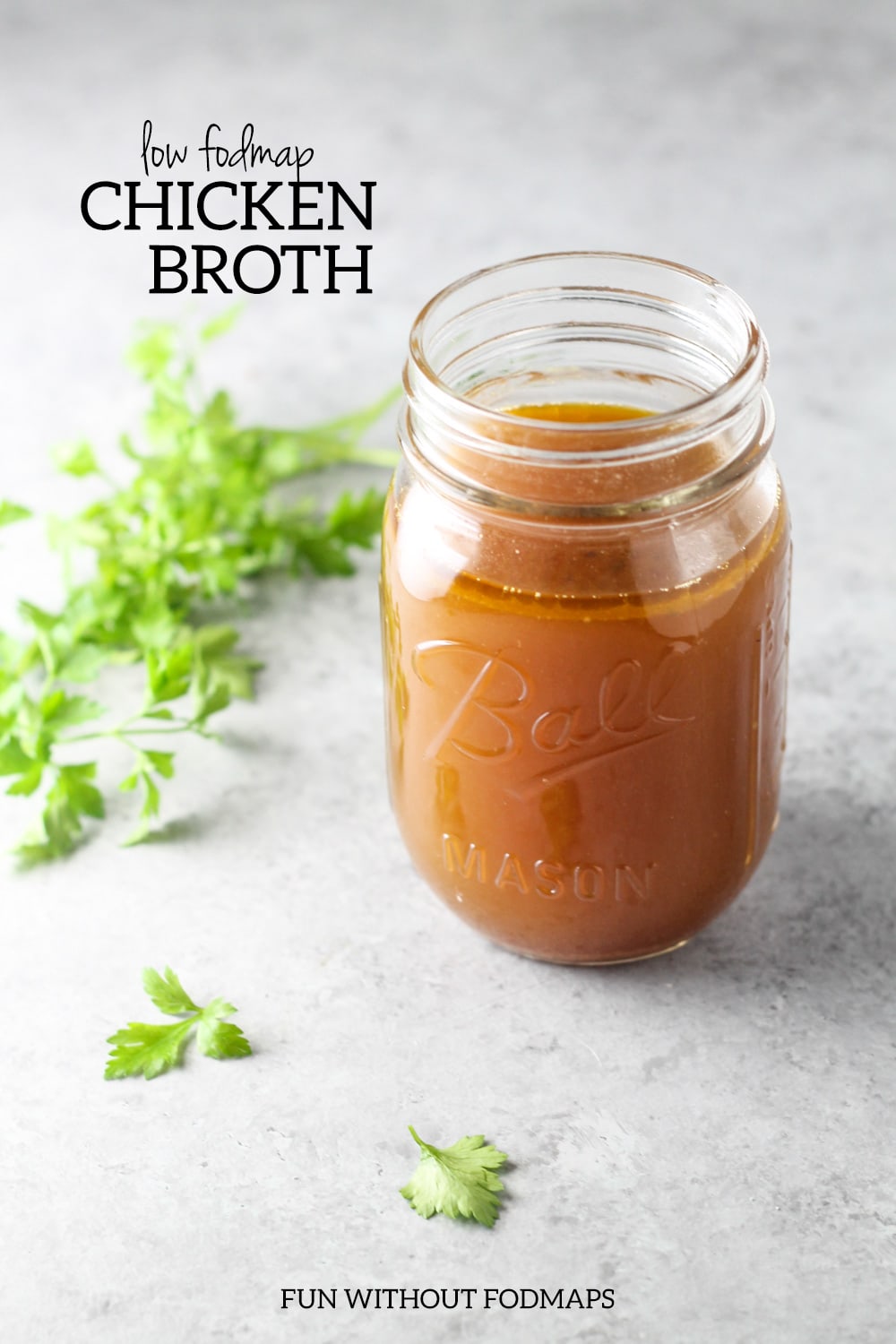A mason jar filled with chicken broth. Next to it, black text reads "Low FODMAP Chicken Broth."