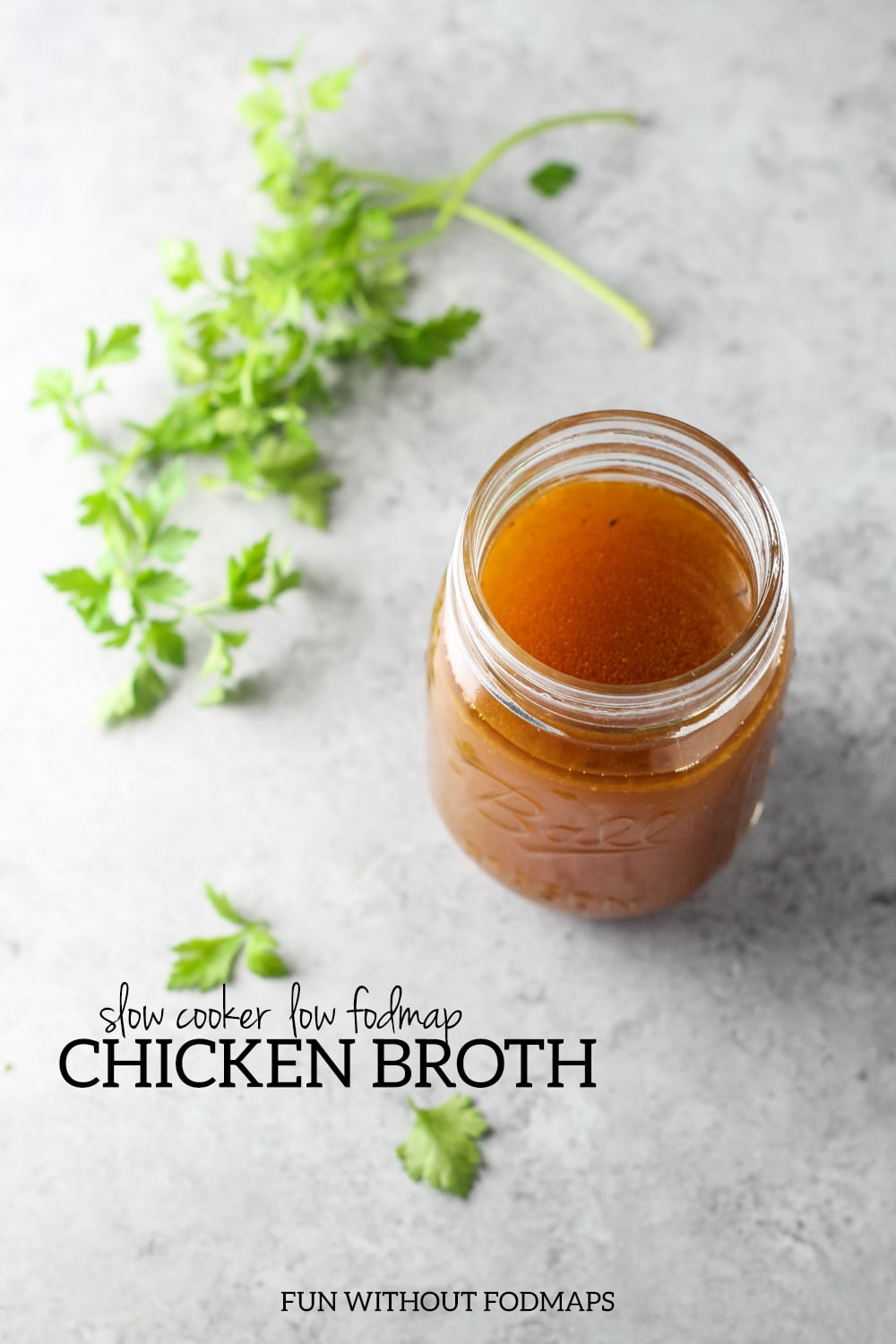 A close up of a jar filled with low FODMAP chicken broth. Next to it, black text reads "Slow Cooker Low FODMAP Chicken Broth."