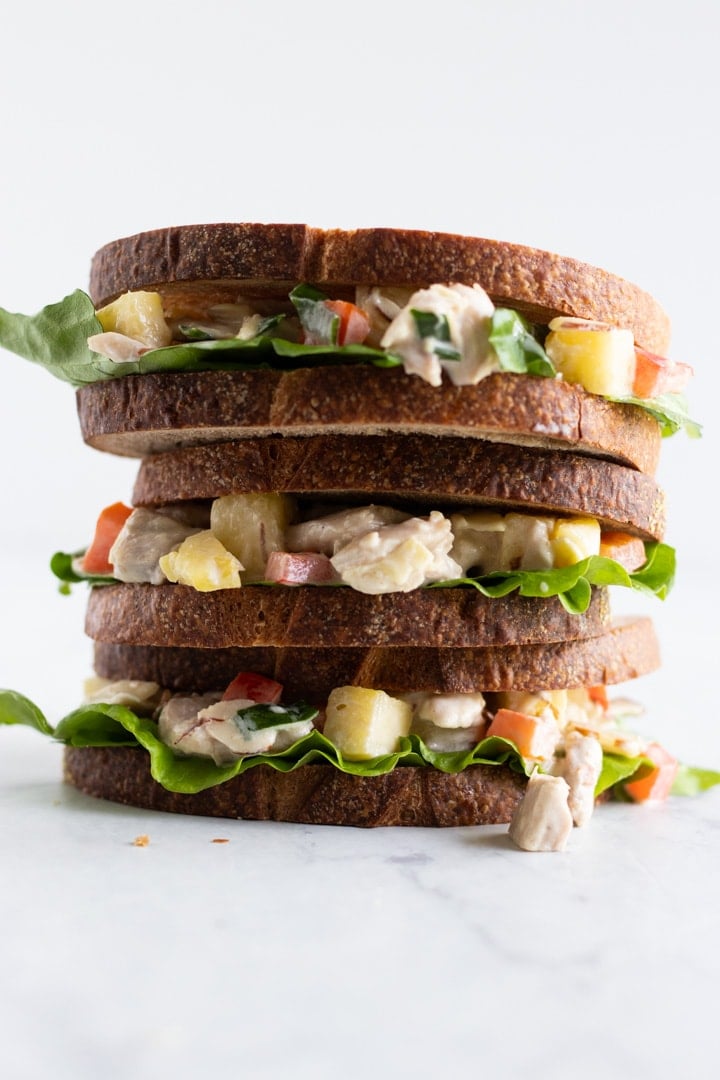 A stack of three sandwiches made with chicken, pineapple, and red bell pepper.