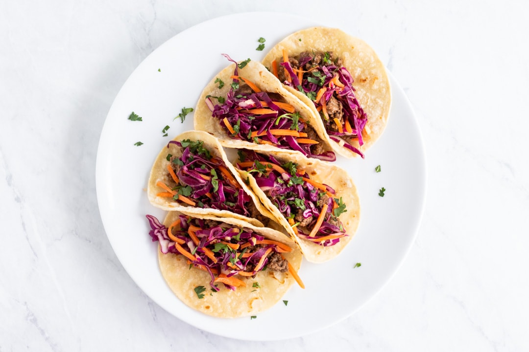 A white plate of colorful low FODMAP Korean tacos garnished with cilantro