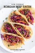 Five tacos made with corn tortillas, ground beef and pickled veggies. In the white space above, black text reads "Low FODMAP Korean Beef Tacos".