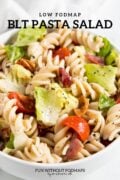 A pasta salad made with cherry tomatoes, romaine lettuce, and bacon. At the top, black text reads "Low FODMAP BLT Pasta Salad".