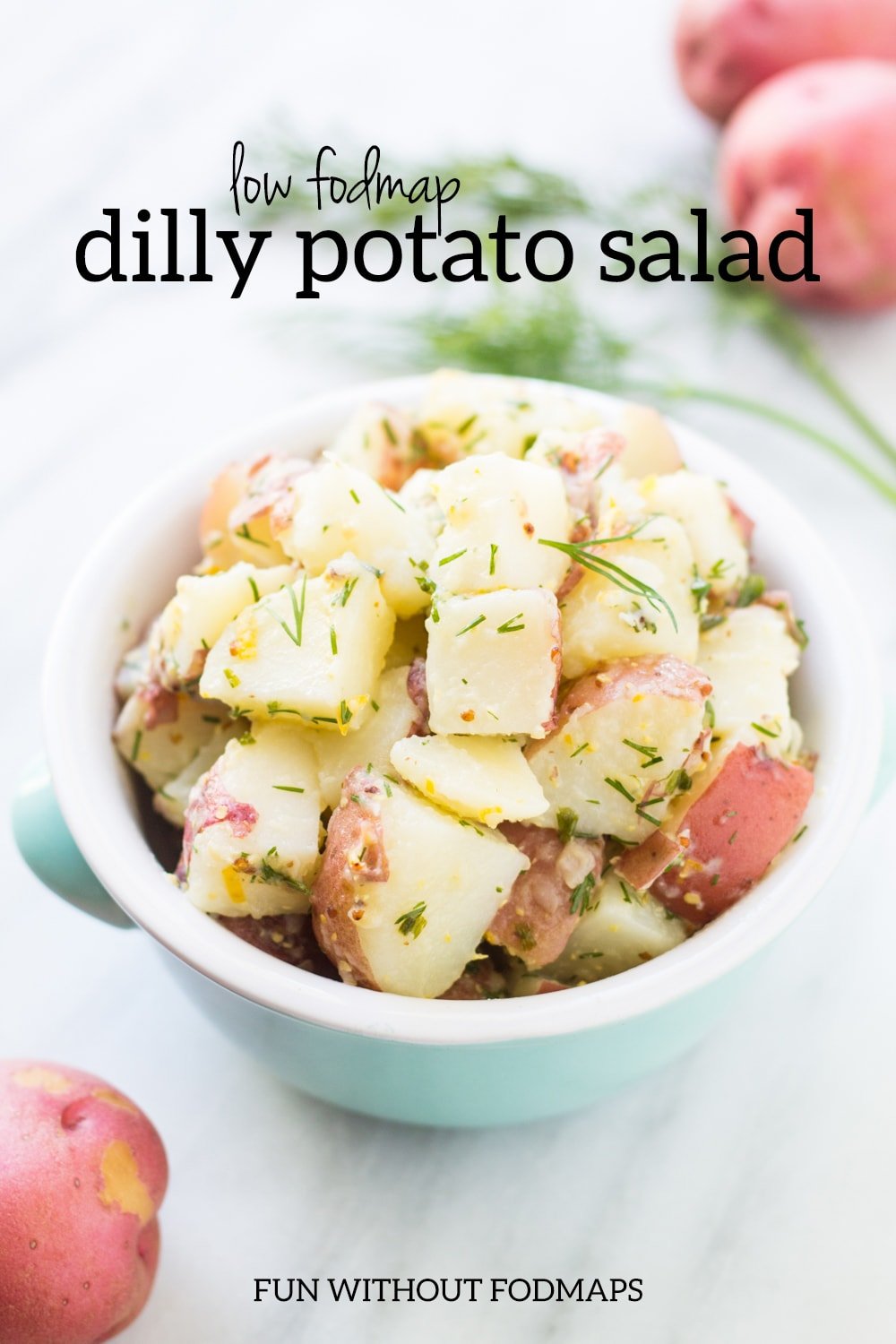 A bowl of cold potato salad flavored with lemon and fresh dill. In the space above the bowl, black text reads "Low FODMAP Dilly Potato Salad."
