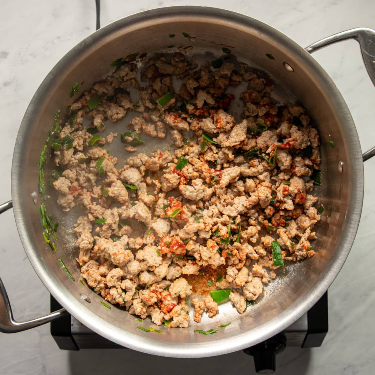 Browned ground turkey mixed with tomato paste in a soup pot. 