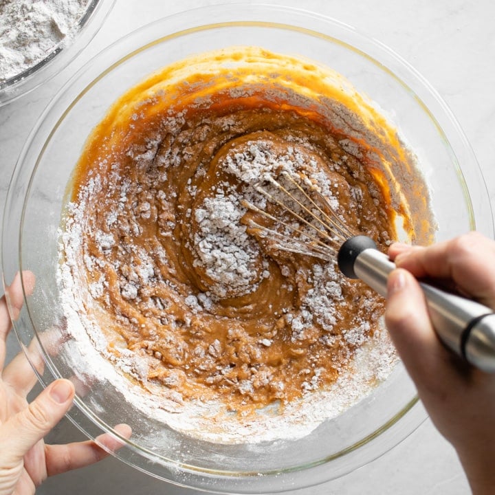 Mixing the wet and dry muffin ingredients in a large glass bowl.