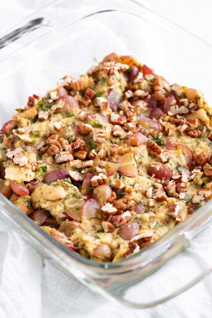A glass baking dish filled with stuffing made with grapes.
